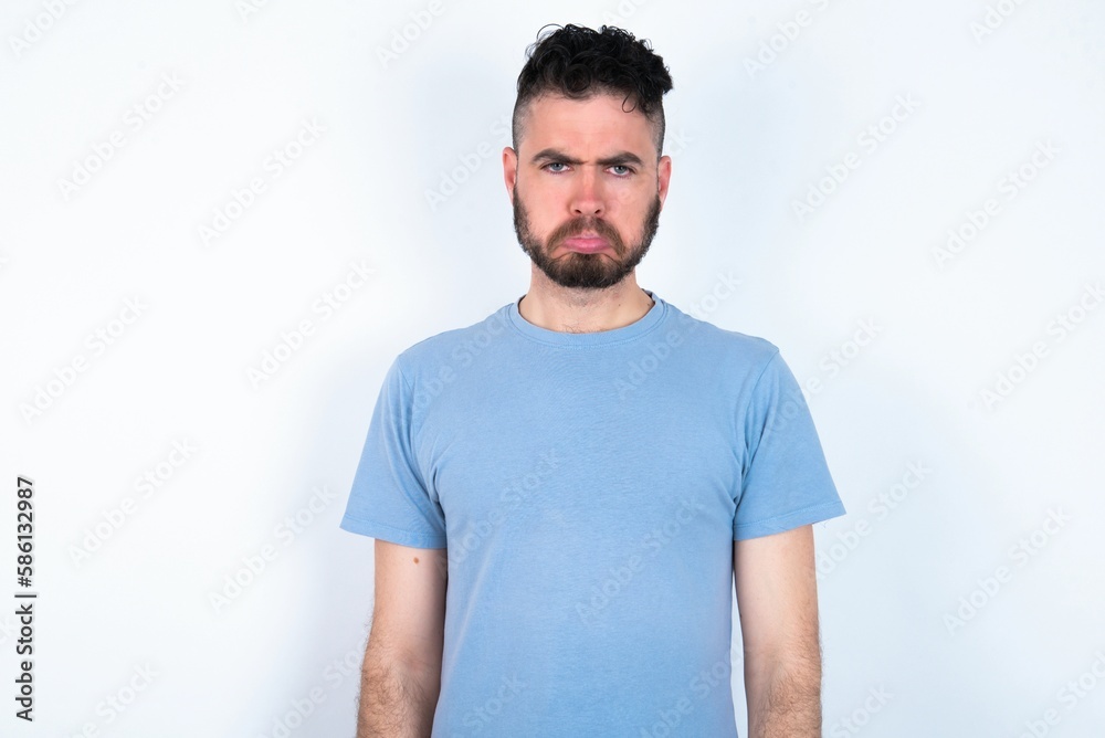 Obraz premium Young caucasian man wearing blue T-shirt over white background depressed and worry for distress, crying angry and afraid. Sad expression.