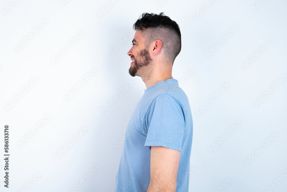 Profile portrait of nice Young caucasian man wearing blue T-shirt over white background look empty space toothy smile Profile portrait of nice Young caucasian man wearing blue T-shirt over white background look empty space toothy smile