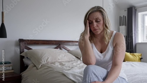 Menopausal Mature Woman Suffering With Low Mood And Anxiety Sitting On Bed At Home 
