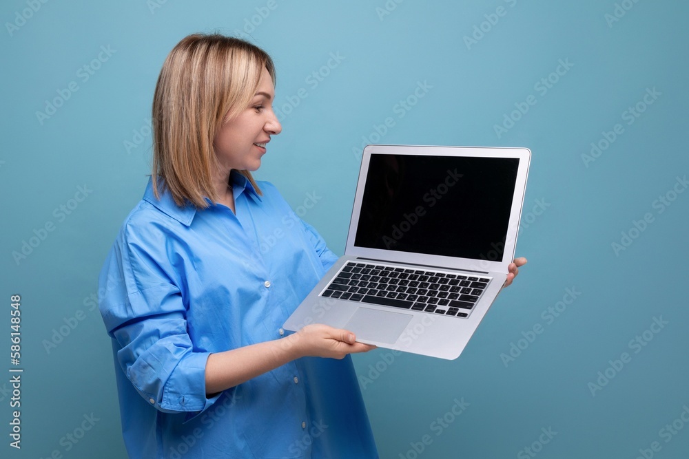 smart attentive young woman in a casual shirt holding a laptop with a mockup in her hands on a blue isolated background with copy space smart attentive young woman in a casual shirt holding a laptop with a mockup in her hands on a blue isolated background with copy space