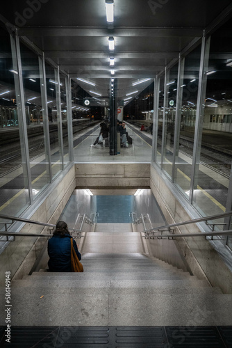 Woman sitting alone on the stairs of a train platform at night