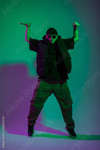 Professional artist dancer man with sunglasses in fashion clothes dancing in creative studio with pink and green color © alones