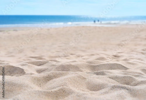 A coastal foreground texture scene to place products on the sand with a blurred sea background on a sunny summer day. photo