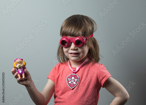 A girl in the costume of the character of the animated series Paw Patrol and with a Sky figurine in her hand. Portrait