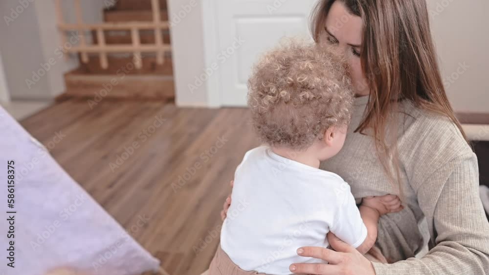 mother comforts curly-haired baby in the room. Slow motion mother comforts curly-haired baby in the room. Slow motion
