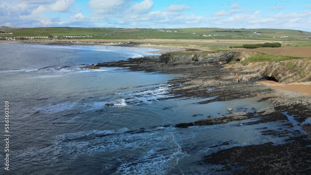 Rocky coast and green ocean, green hills and sandy cove beach, coastal Ireland Rocky coast and green ocean, green hills and sandy cove beach, coastal Ireland