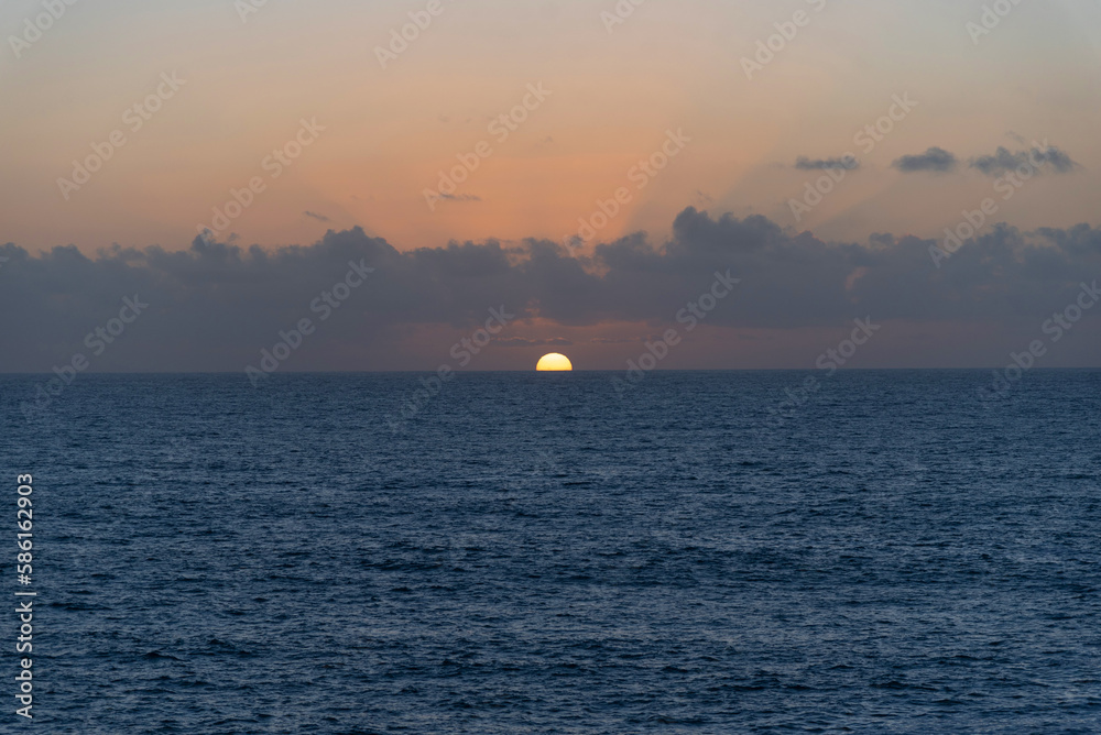 Atardecer con puesta de sol sobre el mar y el horizonte en las costas de Fuerteventura en las Islas Canarias durante un día de verano con cielo despejado.