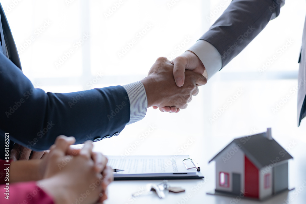 Real estate agent shaking hands with a client to sign a home purchase contract and congratulate the client.