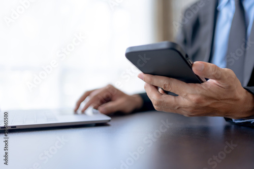 Businessman using smartphone to send text messages in the office.
