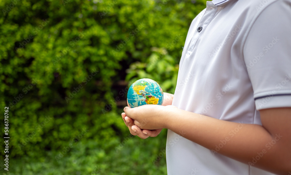 Planet earth in the boy's hands saves and protects the world over blurred green nature background. Environmental concept on Earth Day. Planet earth in the boy's hands saves and protects the world over blurred green nature background. Environmental concept on Earth Day.