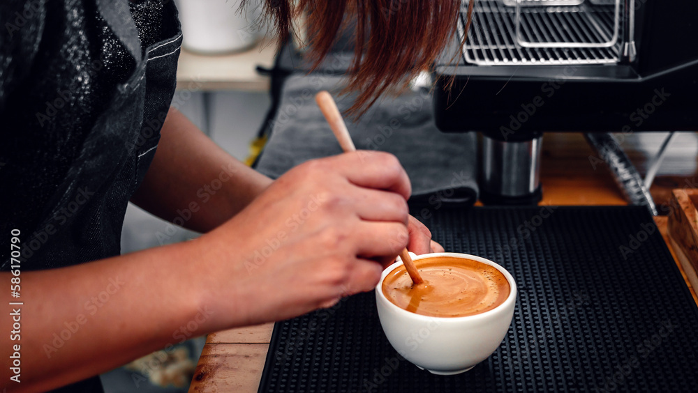 barista making coffee, the hand of a barista with a wooden spoon making or preparing coffee foam in a cup of coffee. barista making coffee, the hand of a barista with a wooden spoon making or preparing coffee foam in a cup of coffee.
