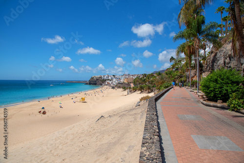 Vista panorámica de la playa de arena blanca y aguas turquesas de Morro Jable en Fuerteventura, desde un paseo peatonal con vistas al resto del pueblo en un día soleado en las Islas Canarias. © Safi