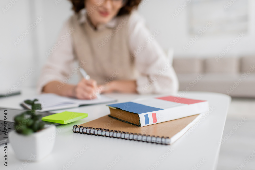dictionary book on notepad near student taking notes during lesson on blurred background. dictionary book on notepad near student taking notes during lesson on blurred background.