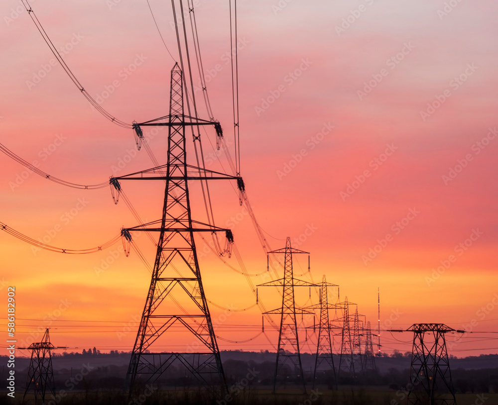 Silhouette electric pylons against an orange sky
