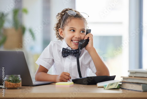 Children, telephone and a girl playing in an office as a fantasy businesswoman at work on a laptop. Kids, phone call and a female child working at a desk while using her imagination to pretend