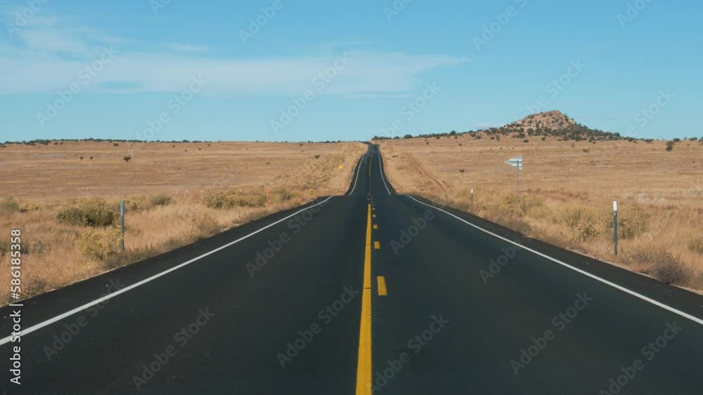 Driving on highway of black asphalt and yellow road markings, pass through desert prairie with dried yellow grass, in western usa national park. Slow motion, view from car. Cargo delivery goods