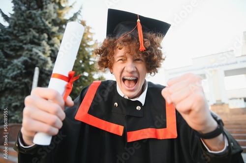 Excited male student in mantle scream graduate from university finish course studying. Happy man triumph holding college diploma in hands overjoyed with high school graduation.