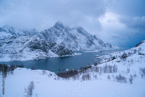 Stunning winter landscape of the Lofoten Islands in Norway. The mountains in the background rise up majestically, with their peaks covered in snow. Majestic natural wonders of the world. Travel