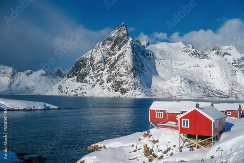 Fishing Village Hamnøy with snow covered Rorbuer. Town and fisherman's cabins or Rorbus in front of snowy mountains, winter, Hamnøy, Moskenesøy, Lofoten, Norway photo