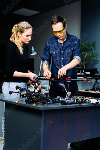 Man and woman engineers working on racing fpv drone combat kamikaze bomber in workshop