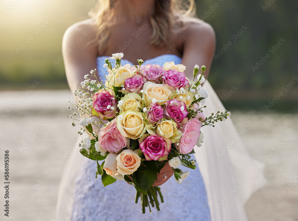 Naklejka premium Closeup, bride and flower bouquet outdoor for celebration of commitment, ceremony and marriage. Woman, wedding and holding roses, spring flowers and floral blossom to celebrate love at elegant event
