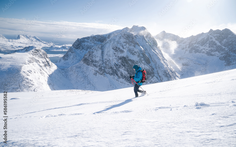Adventurous man during a winter mountain climb. The man appears to be determined and focused as he carefully navigates his way up the steep terrain. Spirit of winter adventure. Challenging conditions