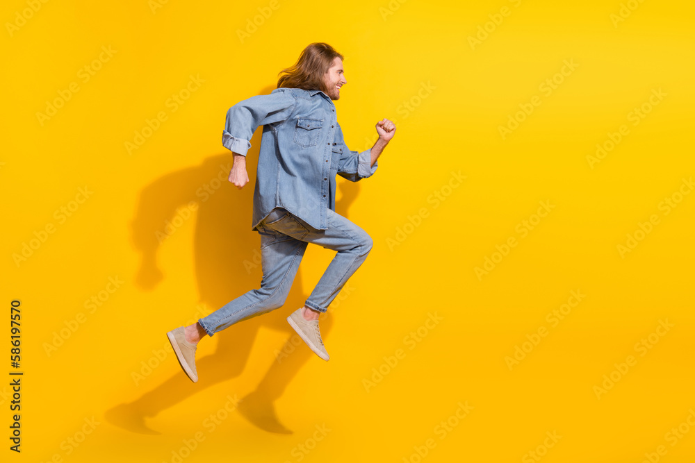 Full length photo of funky cool guy dressed jeans shirt jumping high running emtpy space isolated yellow color background