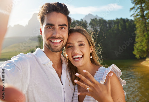 Couple, portrait selfie and engagement by lake for celebration, happiness and excited for future. Man, woman and photography for social media, profile picture and romance for love, proposal and goals photo