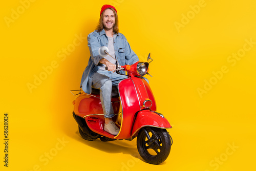 Full length photo of funny cheerful guy dressed jeans shirt driving vehicle isolated yellow color background © deagreez