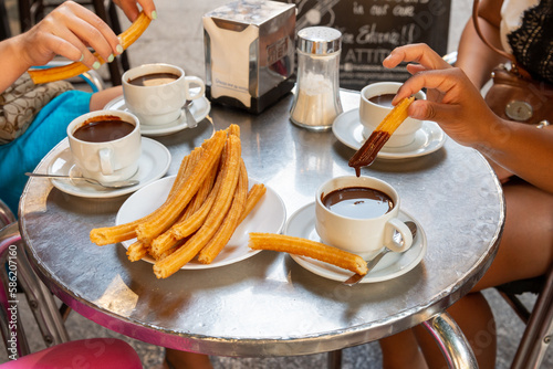 People eating churros and hot chocolate drinks, Madrid, Spain photo