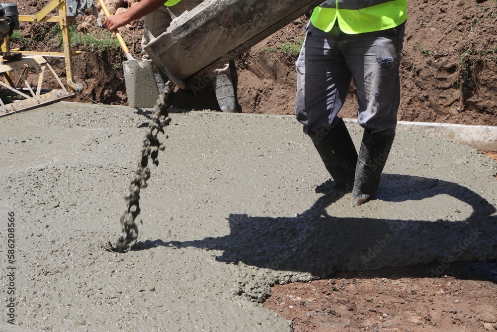 A construction worker unloads concrete from a concrete mixer truck to pave a street. A construction worker unloads concrete from a concrete mixer truck to pave a street.