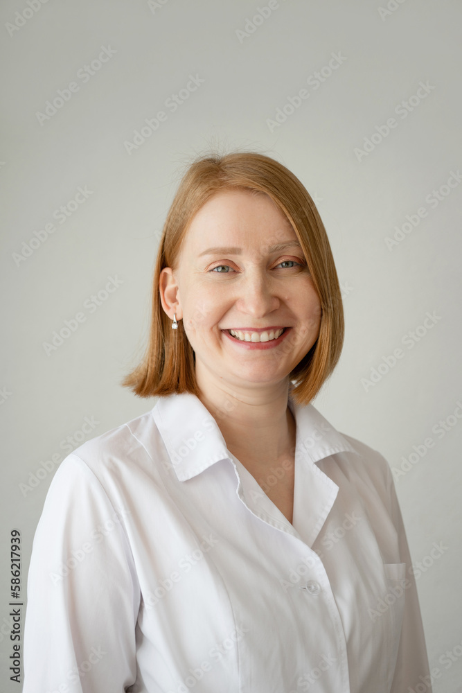 Smiling woman in white coat standing in studio Smiling woman in white coat standing in studio