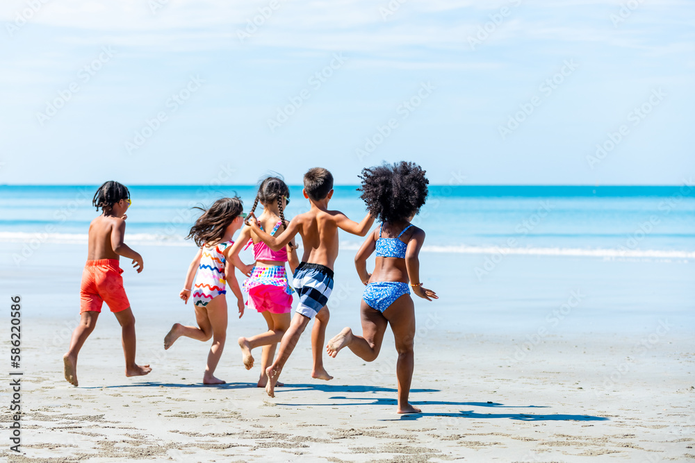 Group of Diversity little child boy and girl friends running and playing sea water at tropical beach together on summer vacation. Happy children kids enjoy and fun outdoor lifestyle on beach holiday.