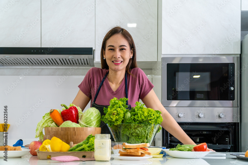 Asian woman photographed with a variety of salads on the kitchen counter with a smiling face. Asian woman photographed with a variety of salads on the kitchen counter with a smiling face.
