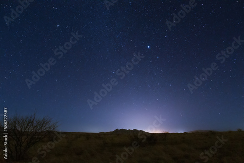 The starry night sky appearing at the end of daylight over the landscape.