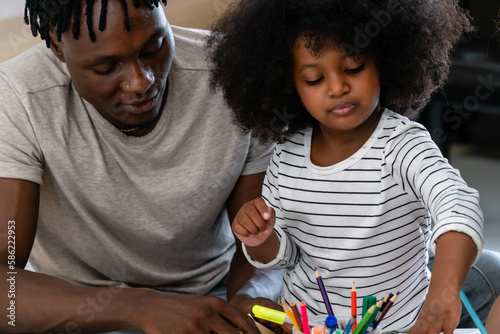 A black american father  his daughters are doing their homework in the living room.