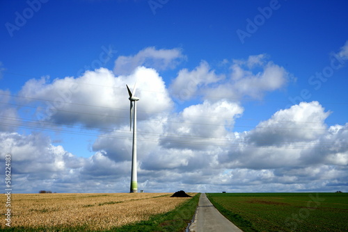 Windrad auf einem Feld im Frühling beinlauem Himmel mit weißen Wolken im Sonnenschein in Greste bei Asemissen und Leopoldshöhe am Teutoburger Wald in Ostwestfalen-Lippe photo