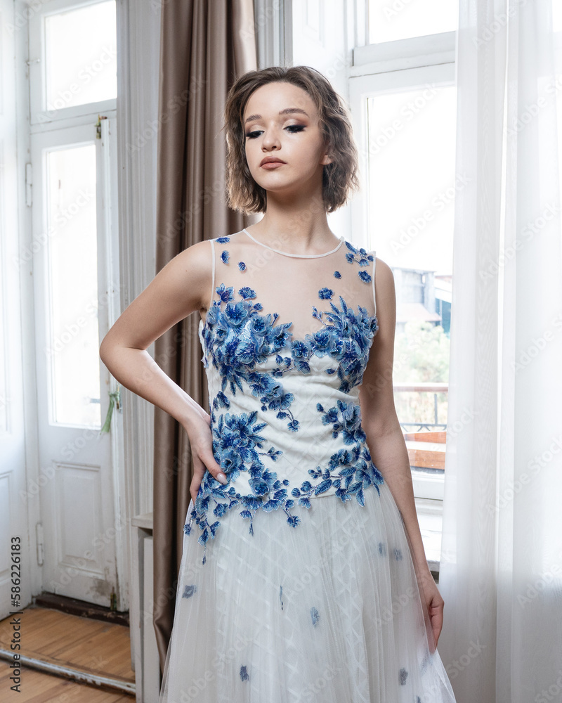 A woman in a white dress with blue flowers