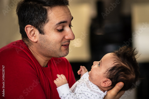 Happy father looks at his newborn son with tenderness