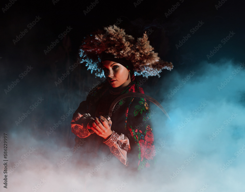 Ukrainian witch - woman in traditional costume with sickle in reeds at night.