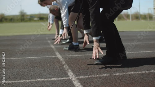 Businessmen stand on starting line of stadium preparing for the race, close-up of the legs. Concept business competition