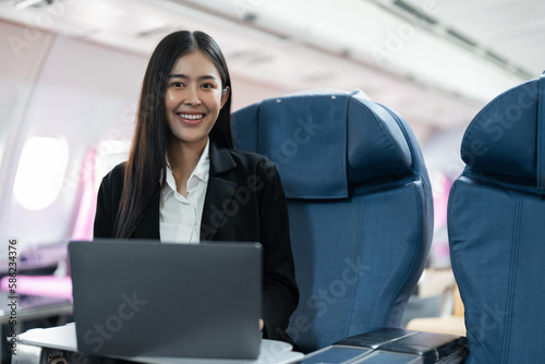 Female passenger sitting on plane while working on laptop computer with simulated space using on board wireless connection © Natee Meepian