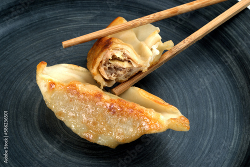 Chicken gyozas with chopsticks on plate photo