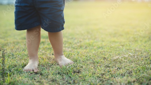 Closeup.child walking barefoot on green grass with the light of the sun