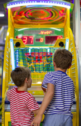 Entertainment center and children's area with slot machines. Two boys throws basketball in basket. Basketball arcade game.