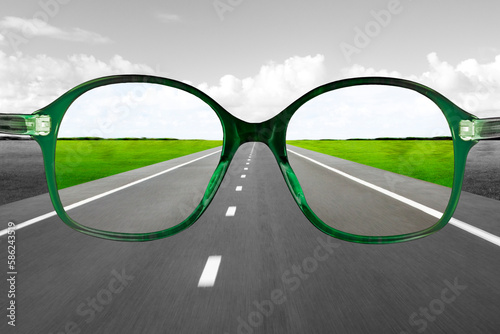 Grüne Lesebrille vor einer unscharfen Strasse als  Hintergrund
