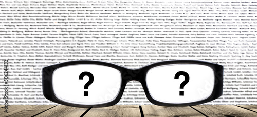 Brille mit Fragezeichen vor Unscharfem Texthintergrund