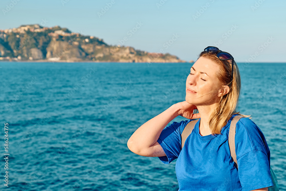 Portrait of blond woman tourist with closed eyes enjoying freedom by the sea. Female traveler relaxing in serene nature. Mental health, wellness, adventure travel and healthy lifestyle. Portrait of blond woman tourist with closed eyes enjoying freedom by the sea. Female traveler relaxing in serene nature. Mental health, wellness, adventure travel and healthy lifestyle.