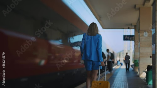 Woman walks along the platform at the train station.