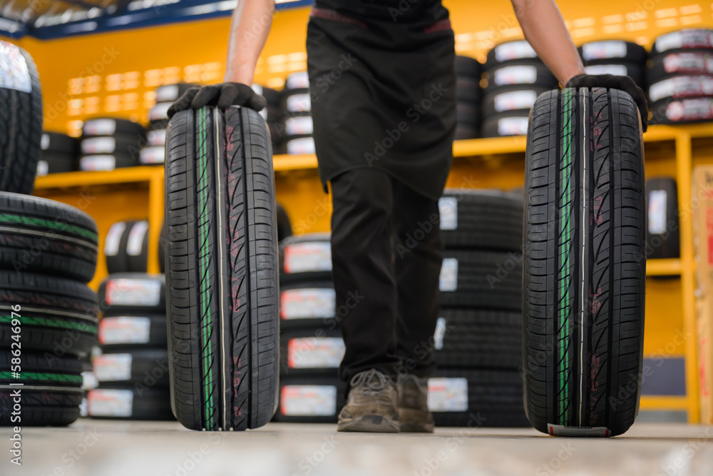 Fototapeta premium A tire changer checks new tires in stock to take them to a service center or wheel shop. Tire warehouse for the automobile industry